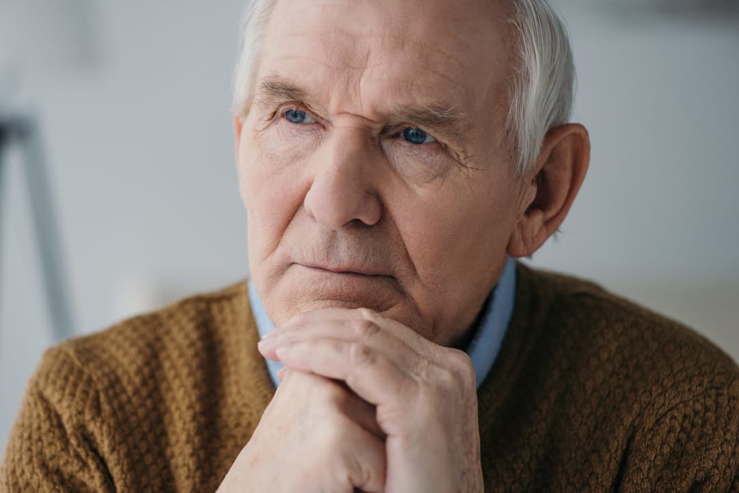 Thoughtful senior man resting his chin on his hands